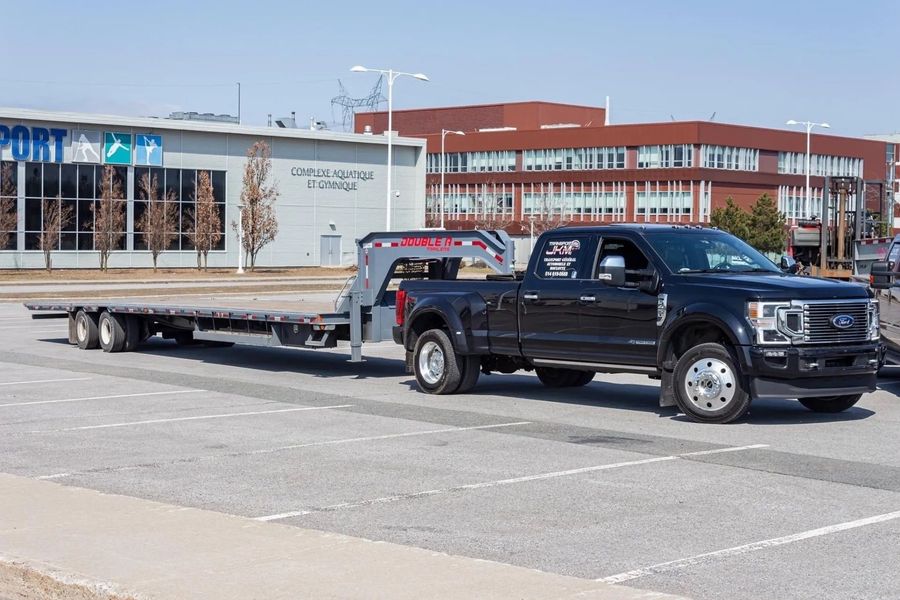 Camion noir Transport JKM attelé à une remorque à plateforme