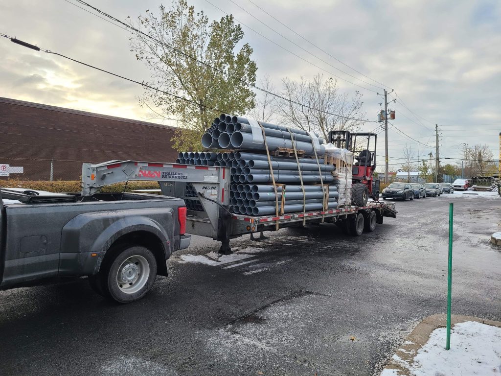 Camionnette Transport JKM et remorque chargée de tuyaux.
