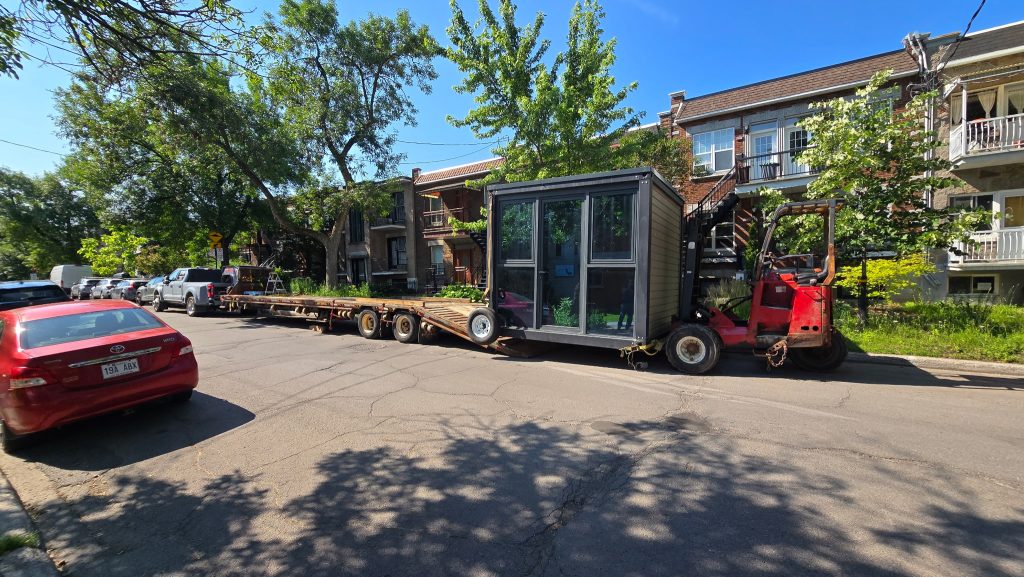 A glazed module and red forklift beside a Transport JKM trailer.