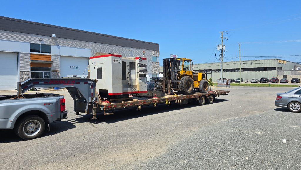 An industrial machine and yellow forklift loaded on a trailer.