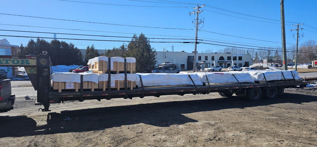 A long flatbed loaded with wrapped goods and pallets.
