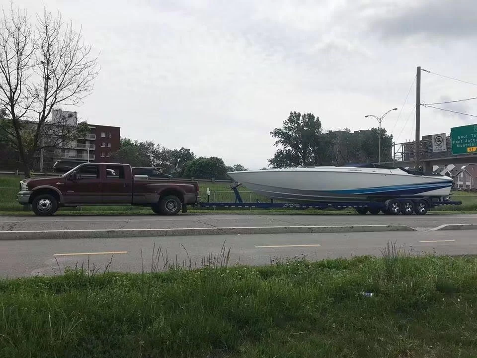 Bateau blanc et bleu sur sa propre remorque, tirée par une camionnette.