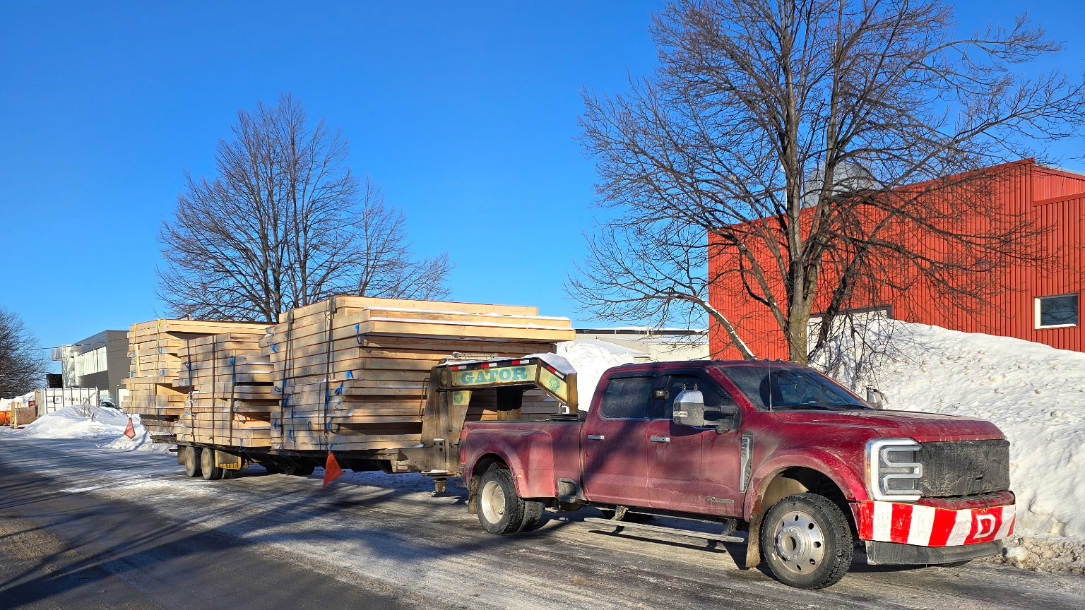 A red Transport JKM truck with a trailer loaded with lumber