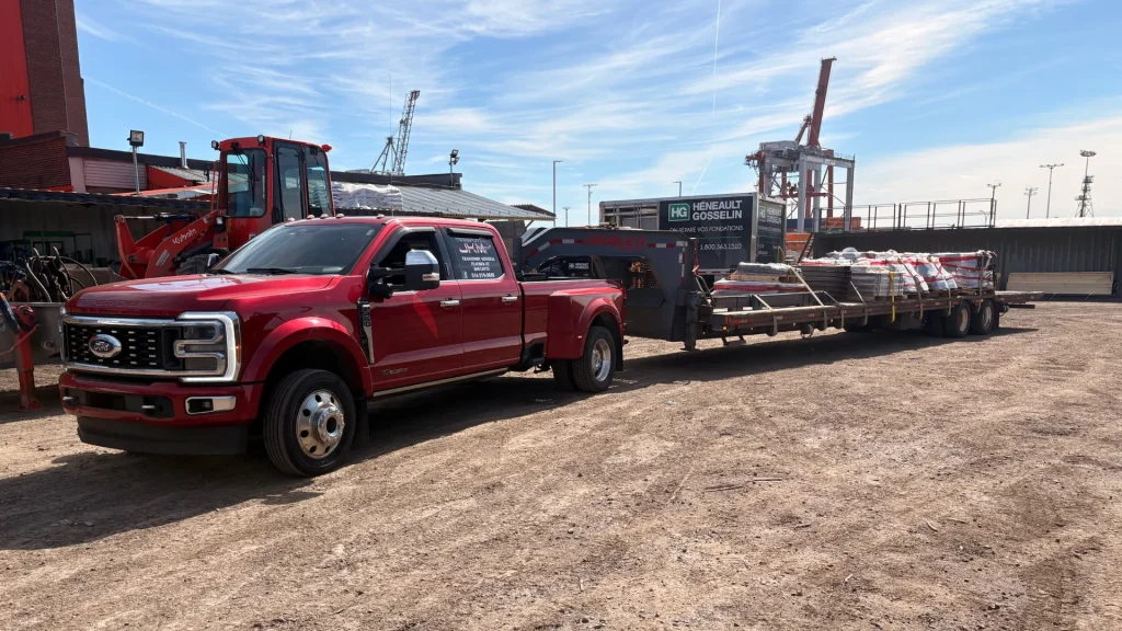 A red Transport JKM truck and loaded trailer on a job site